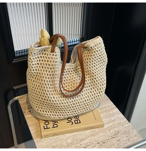 Nahaufnahme der beigen Häkeltasche mit braunen Ledergriffen auf Marmorplatte