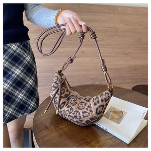 Dettaglio borsa a mezzaluna leopardata con manico in corda intrecciata e fibbie d'oro