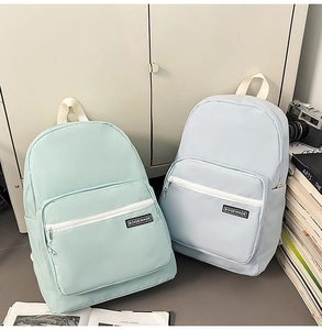 Detail of mint green and blue backpacks with front zipper pockets and brand logos