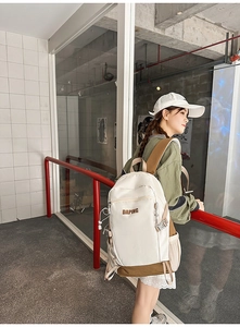 Detail of a beige and brown nylon travel backpack with DAPING logo on a model outdoors