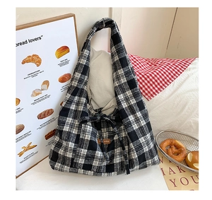 Detail of checkered tote bag with brown leather patch on textured fabric background
