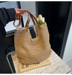 Detail der geflochtenen Tasche mit braunen Ledergriffen und goldenen Nietendetails