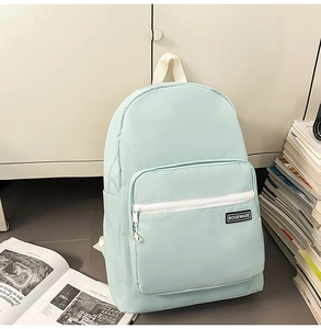Close-up of mint green backpack featuring white front zipper and minimalist brand label