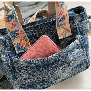 Detail of denim tote bag showing functional front pocket holding a pink leather wallet