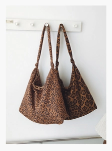 Détail de deux sacs hobo léopard avec bandoulières nouées sur des crochets blancs