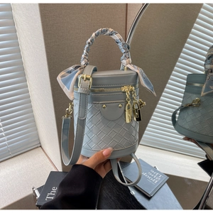 Detail of light blue bucket bag featuring woven texture and scarf-wrapped top handle