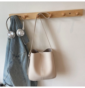 Detail of a beige leather bucket bag with vertical stitching and matching strap