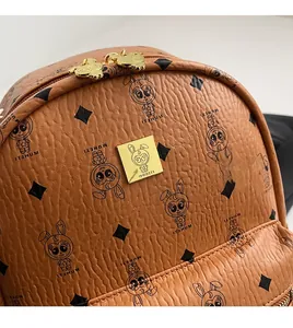 Detail of a brown leather backpack with rabbit prints and a gold logo plate