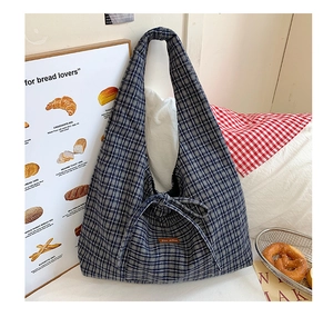 Detail of checkered tote bag with bow tie, thick canvas fabric and leather brand tag