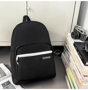 Close-up of minimalist black backpack with contrasting white zipper and brand label details