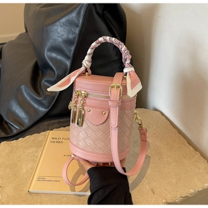 Close-up of pink woven bucket bag with elegant silk scarf wrap and golden zipper detail