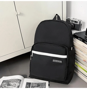 Detail of minimalist black backpack featuring brand label and functional side pockets