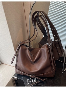 Brown large leather tote bag with lychee texture and adjustable strap on a studio set