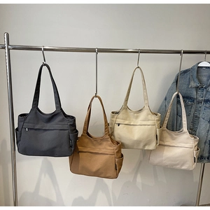 Dettaglio di grandi borse tote in tela dai toni neutri con tasche laterali capienti