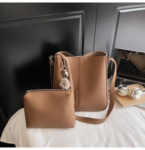 Close-up of brown pebbled leather tote bag with matching pouch and owl keychain charm