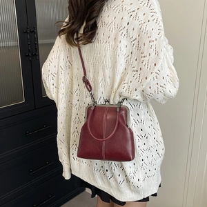Detailed view of a vintage burgundy shell bag with white stitching and metal clasp