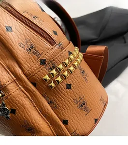 Detailed close-up of brown faux leather backpack with gold pyramid studs and rabbit print