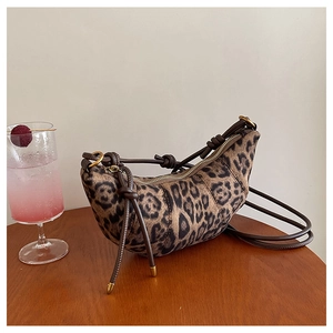 Dettaglio della borsa a mezzaluna leopardata con zip su un tavolo in legno