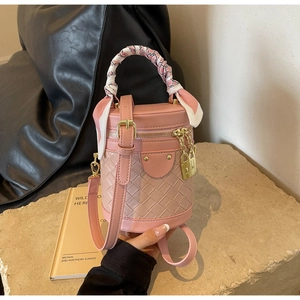 Detail of pink woven bucket bag with elegant silk scarf handle and gold hardware