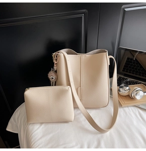 Close-up of beige lychee grain bucket bag set with matching small pouch and pompom charm