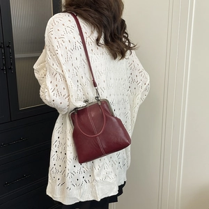 Retro burgundy shell bag with contrast stitching and metal clasp in a lifestyle setting