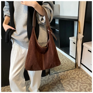 Détail du sac hobo en daim marron montrant la texture riche et la bandoulière en cuir
