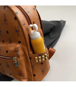 Detail of leather backpack side pocket with gold studs and a yellow water bottle