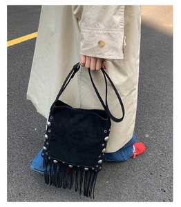 Detail of black suede shoulder bag with silver studs and long fringe tassels