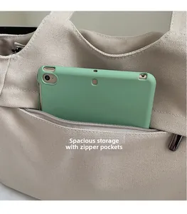 Dettaglio della tasca esterna con zip della borsa tote beige con dentro un tablet