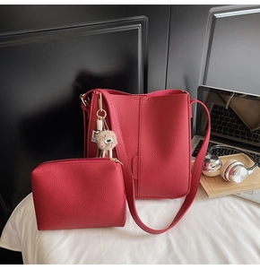 Detail of red lychee leather tote bag set with matching pouch and plush ball accessory