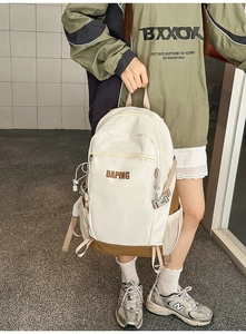 Detail of a beige and khaki travel backpack showing the front pocket with zipper cord