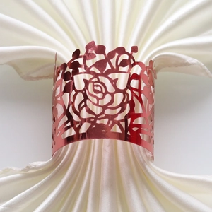 Close-up of rose gold laser-cut floral napkin ring on an ivory satin fabric napkin