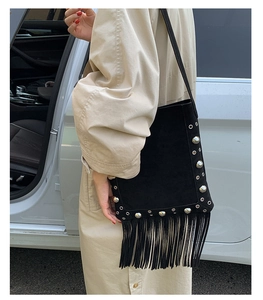 Close-up of black suede shoulder bag with silver studs and long fringe tassels