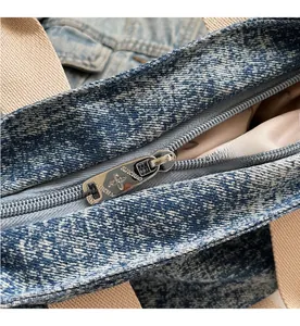 Detailed close-up of premium blue denim tote bag with silver metallic floral zipper puller