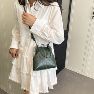 Model showing dark green retro shell bag with metal clasp and leather strap