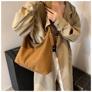 Gros plan du sac hobo en daim marron avec garniture en cuir porté par un mannequin