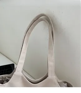 Dettaglio degli spallacci rinforzati e della cerniera sulla borsa tote in nylon beige
