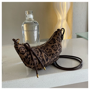 Dettaglio macro della borsa croissant leopardata con hardware dorato e zip lucida