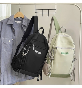 Nylon travel backpacks in black and green hanging against a plaid shirt backdrop