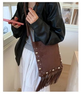 Detail of vintage brown suede crossbody bag with long fringe and silver rivet accents