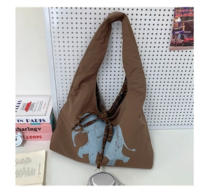 Detail of deep brown tote bag featuring blue elephant print and checkered knot detail