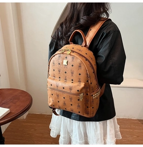 Detailed back view of a brown leather backpack with rabbit prints and gold studs on a model