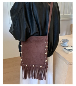 Close-up of brown suede bucket bag featuring rock-style rivets and long fringe tassels