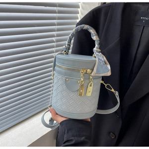 Detail of light blue bucket bag with woven texture, scarf handle and gold lock charms