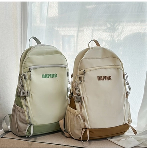 Close-up of light green and beige high-capacity backpacks with side pockets and buckles