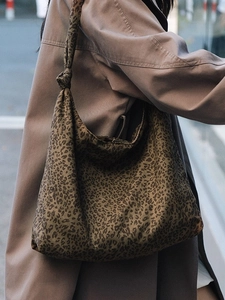 Sac fourre-tout léopard chic avec bandoulière à nœud, porté avec un trench-coat d'automne