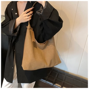 Détail d'un sac hobo marron en daim avec coutures verticales et étiquette
