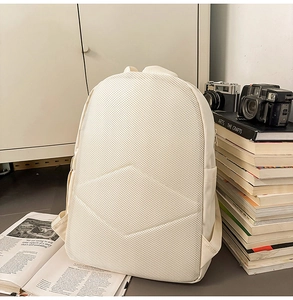 Detail of breathable mesh back and padded adjustable straps on beige backpack