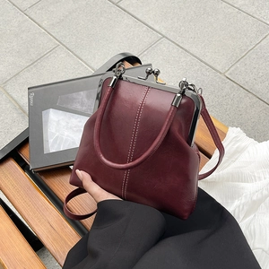 Close-up of retro burgundy shell handbag with white contrast stitching and metal clasp