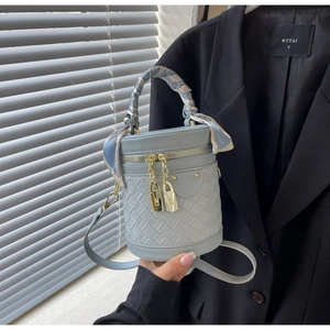 Detail of light blue bucket bag with woven leather base and printed silk scarf handle